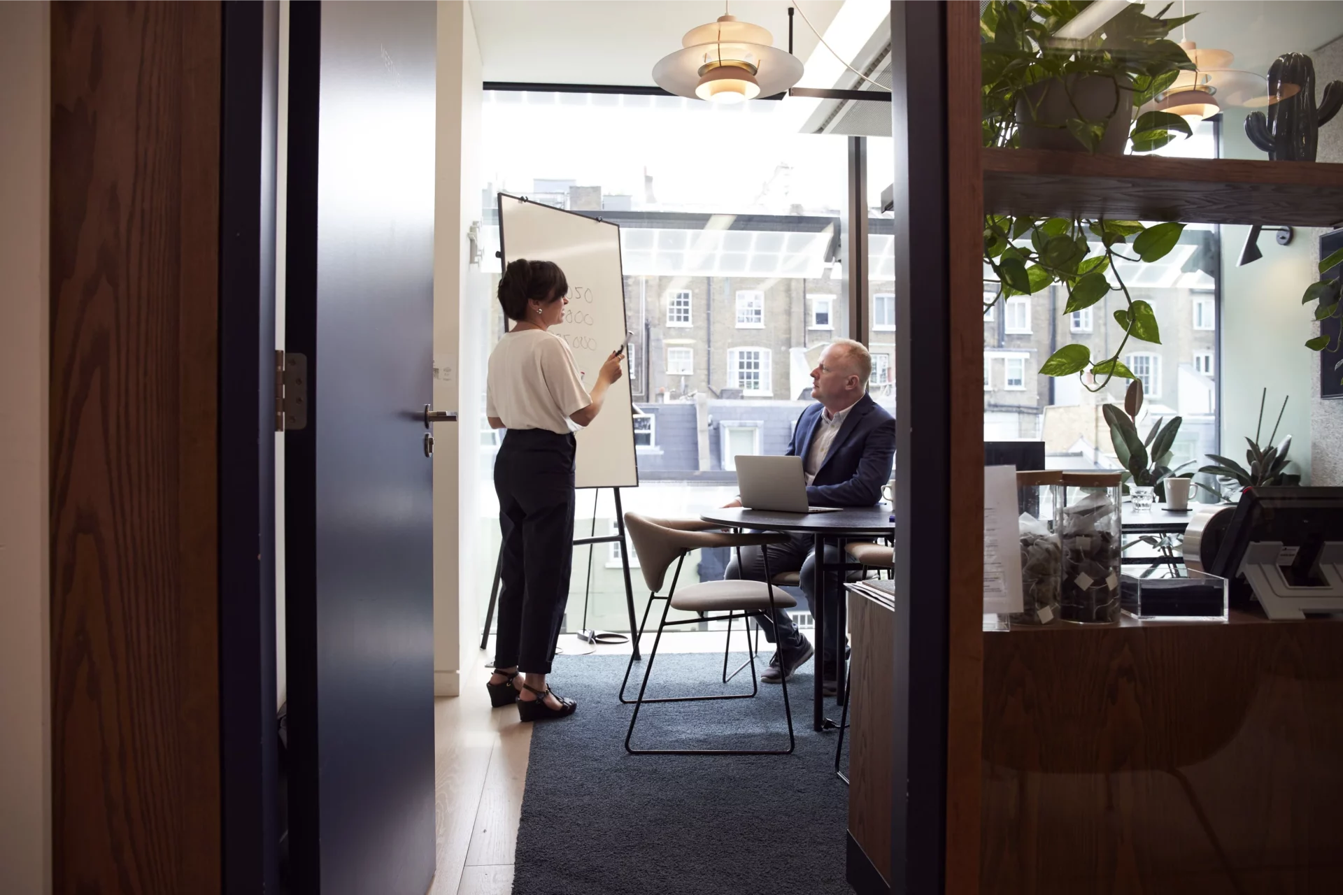 A woman at a white board consulting with a client in a business setting